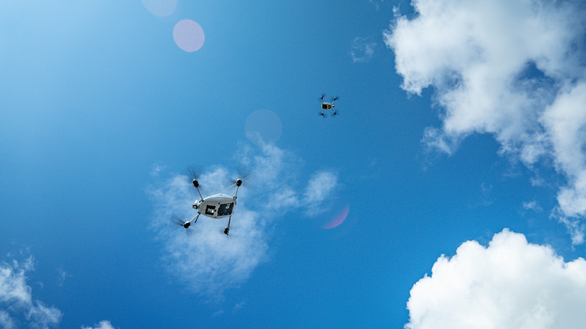 Two Manna aircraft against a blue sky with clouds